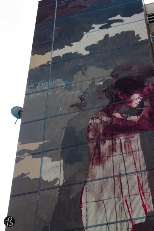 The other mural I wanted to see was the infamous %22bloody refugee” mural that was receiving some controversy over its concept. This huge mural is the work of Spanish artist Borondo and depicts a girl in a white nightgown, covered in blood from the head down. She seems of the leaning against the building on which she is drawn. There is blood on the floor and there is more to it. On the other side of the building you can see a forest with a handcuffed, naked body pierced be arrows. Yeah, this sounds as gore as the moral itself as you can see on the pictures here.