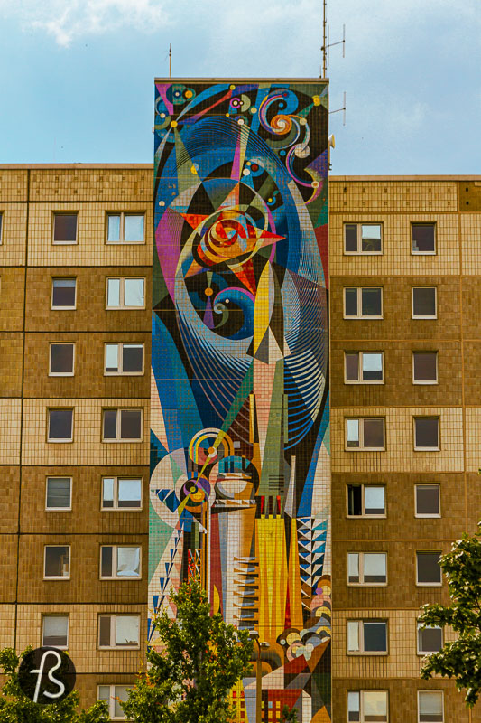 Another mural by the same artist is called "The man-controlled forces of nature and technology" on its left side. At the bottom of this massive socialist mural, you can see workers and miners powering an explosion of industrial force that culminates with the development of technology and science, as can be seen in the colourful representation of the stars on the top of it. This is one of the most beautiful representations of the modern socialist society that we have seen.