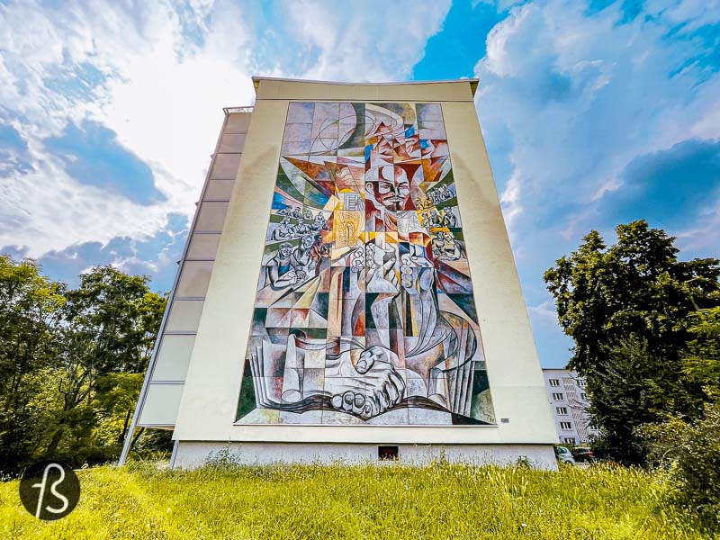 This Lenin mural in Halle Neustadt was unveiled in 1971 by Erich Enge, a bricklayer by training who found himself in large format paintings. His mural is named "He stirred the sleep of the world" and visually presents the three essential reforms that Lenin initiated in the Soviet Union. First, with the elimination of illiteracy, followed by a country comprehensive land reform and the country's electrification in the 1920s. All these elements are presented around Lenin's face in the mural, surrounded by young people reading and learning.