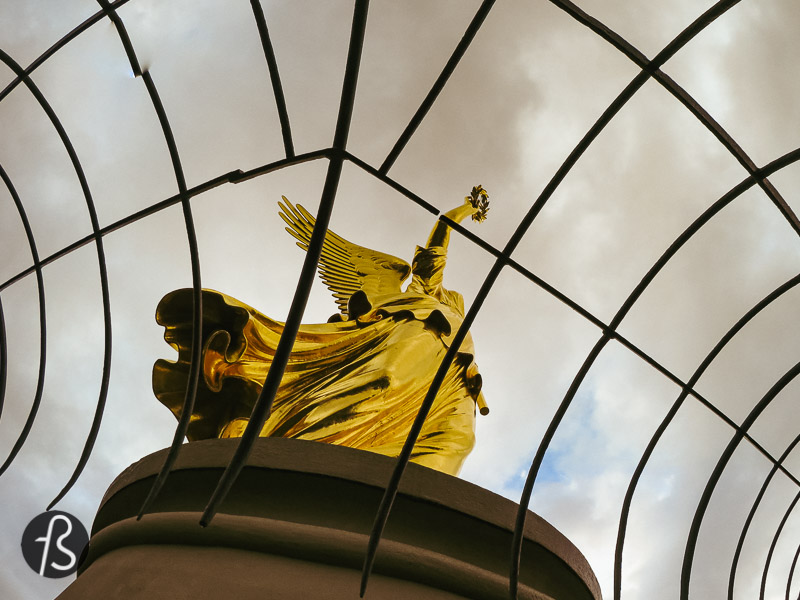 High above the Victory Column, you can find a bronze sculpture of a female form. For some, she might look recognizable as a goddess of ancient mythologies. In Greek mythology, she would be called Nike; in Roman, she was Victoria. Here, since she appears with an eagle helmet, she is Borussia, the personification of Prussia.